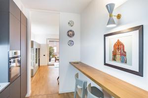 a kitchen with white walls and a counter with chairs at Appartamento Peschiera Borromeo - Linate in Peschiera Borromeo