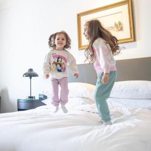 two little girls jumping on top of a bed at Hyatt Regency Baku in Baku