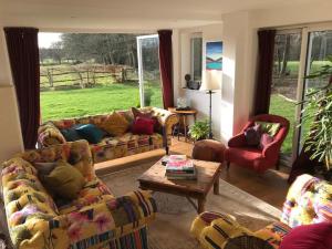 a living room with couches and a table and a window at A House in the Woods in Chiddingly