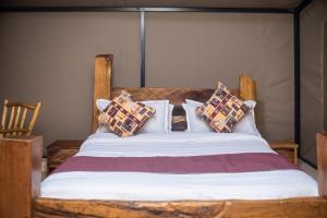 a bedroom with a wooden bed with pillows on it at OLORIEN MARA CAMP in Masai Mara