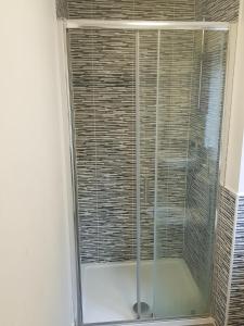 a shower with a glass door in a room at Dengenzy House in Seacroft