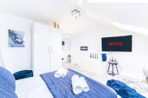 a white bedroom with a blue bed and a tv at Luxury Apartment - Close to City Centre - Free Parking, Fast Wifi and SmartTV by Yoko Property in Coventry