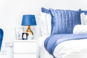 a blue bed with white pillows and a blue lamp at Luxury Apartment - Close to City Centre - Free Parking, Fast Wifi and SmartTV by Yoko Property in Coventry