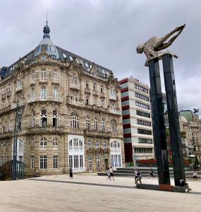 um grande edifício com uma estátua em frente em Edificio El Moderno, Vigo 1.902 em Vigo