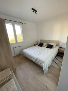 a white bedroom with a bed and a window at Maison mitoyenne 60m2 en campagne in Montailleur