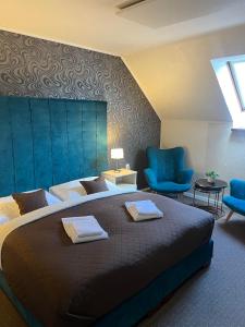 1 dormitorio con 1 cama grande y sillas azules en Penzión Aira en Zvolen