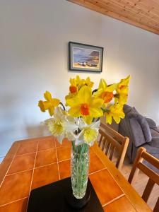 a vase of yellow and white flowers on a table at Crega Cottage in Malin Head