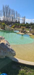 ein großer Pool mit einem Felsen in der Unterkunft Mas des Cerisiers SPA-SAUNA inclus pour tous les logements in Avignon