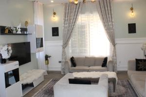 uma sala de estar com mobiliário branco e uma grande janela em ISN Luxury Apartments em Dodoma