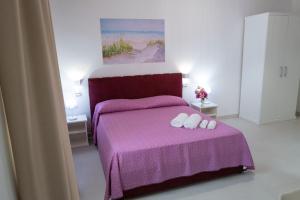 1 dormitorio con 1 cama morada y 2 toallas blancas en Stellaris en Siderno Marina