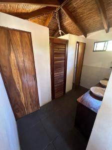 baño con lavabo y puerta de madera en Surfing Turtle Lodge en Poneloya