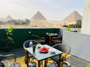 una mesa y sillas en un balcón con pirámides en Capital Of Pyramids Hotel, en El Cairo