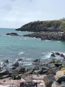 a rocky shoreline with the ocean and a rocky island at Lochside Retreat, Stranraer - Cottage by the loch! in Stranraer