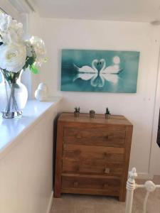 a wooden dresser with a vase of flowers and a painting at Lochside Retreat, Stranraer - Cottage by the loch! in Stranraer
