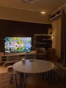 uma sala de estar com uma mesa e uma televisão grande em شقة غرفة وصالة بلكونه دخول ذكي em Riyadh