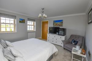 a bedroom with a bed and a chair and a television at Sunset View at The Dovecote in Kirkby on Bain