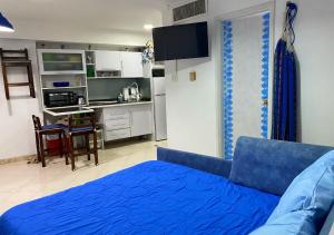 sala de estar con cama azul y cocina en Miramar en Porlamar