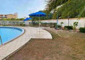 a pool with a table and a blue umbrella at Miramar in Porlamar