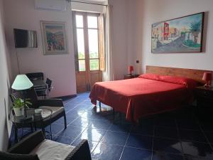 a bedroom with a red bed and a table and chairs at Bed & Breakfast Maredomus in Milazzo