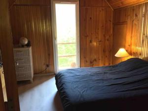 ein Schlafzimmer mit einem Bett, einem Fenster und einer Lampe in der Unterkunft Chalet de Montagne in Valdeblore