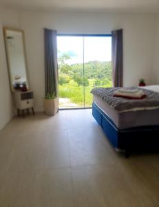 Schlafzimmer mit einem Bett und einer großen Glasschiebetür in der Unterkunft Fazenda de Jehne - Casa completa in Camamu