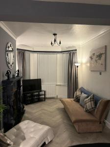 uma sala de estar com um sofá e uma televisão em Manor House em Belfast