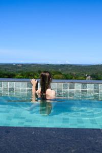 una mujer está sentada en una piscina en Fazenda de Jehne, en Camamu