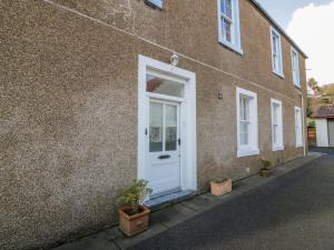 a white door on a brick building with potted plants at Lower Neuk in Dunfermline