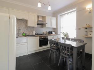 a kitchen with white cabinets and a table with chairs at Lower Neuk in Dunfermline