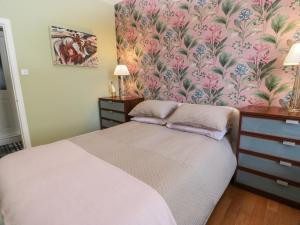 a bedroom with a bed with a floral wallpaper at Lower Neuk in Dunfermline