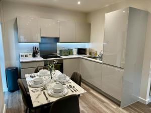 a kitchen with a table with plates and glasses on it at Luxury Apt in Wembley Park Perfect for Events & Exploring London in London