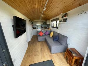 una sala de estar en una casa pequeña con sofá en Maple Lodge Quirky Salvaged Railway Carriage with Hot Tub en Boston