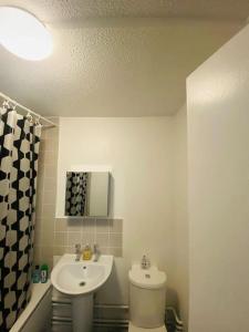 a white bathroom with a sink and a toilet at Spacious One Bedroom Flat close to Heathrow Airport in Northolt