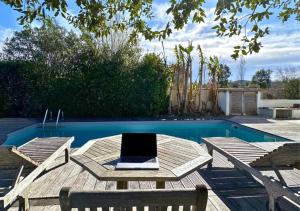 einen Pool mit einem Tisch, 2 Stühlen und einem Laptop in der Unterkunft Villa COLIVING EFFET MER - Nomad Digital - 4 chambres in Anglet