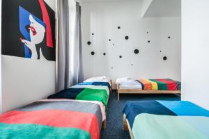 um quarto com três camas com cobertores coloridos em Pop Art Rooms em Praga