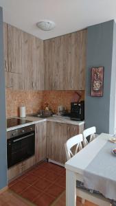 una cocina con armarios de madera y una mesa blanca con sillas. en Apartman LiBra, en Banja Koviljača