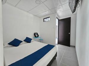 a bedroom with a white bed with blue pillows at tour & hosteleria moonlight in Villavieja