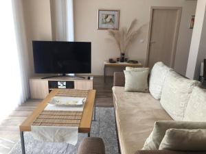 een woonkamer met een bank en een tv bij Obzor Beach Resort Beachfront in Obzor