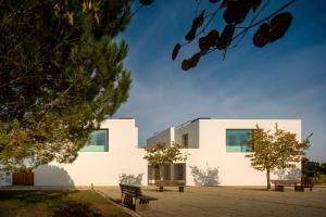 a white building with benches in front of it at Square House . Comporta, Portugal in Comporta