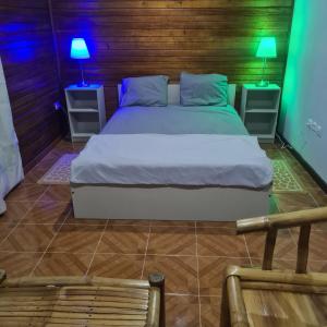 a bedroom with a bed and two night stands with lamps at Beachbungalows STP in M. Peixe