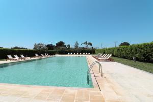 una grande piscina con sedie a sdraio e alberi di Casa Aleatico Residence Torre Santo Stefano in Otranto ad Alimini