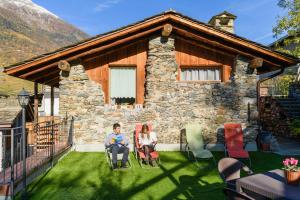 a man and woman sitting in lawn chairs in front of a house at Ostello del Castello Tirano in Tirano