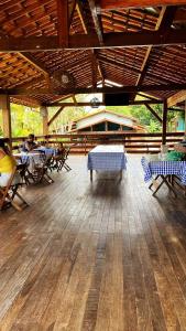 a patio with tables and chairs on a wooden floor at Fazenda Lagoa Azul in Silva Jardim