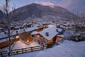 a house covered in snow with a mountain in the background at Ostello del Castello Tirano in Tirano