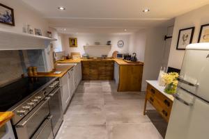a large kitchen with white appliances and wooden cabinets at Dene Croft Cottage in Hexham