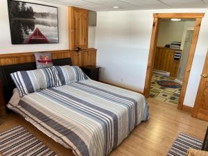 a bedroom with a bed with a striped comforter at Fiddler's Lake Escape in Gabarus