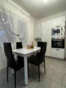 eine Küche mit einem weißen Tisch und schwarzen Stühlen in der Unterkunft Beauty and Beast in Ponzano Veneto