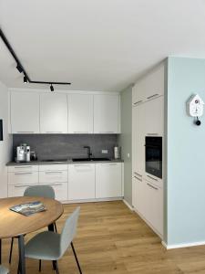a kitchen with white cabinets and a wooden table at Coucou - Nest im Schwarzwald in Gengenbach