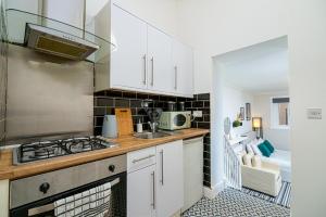 a kitchen with white cabinets and a stove top oven at Highbury & Islington Hub in London