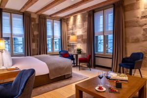 a hotel room with a bed and chairs and windows at Hôtel Les Armures in Geneva